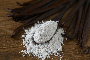 Fototapeta na wymiar vanilla beans with aromatic sugar on dark wooden surface