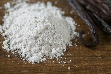 vanilla beans with aromatic sugar on dark wooden surface