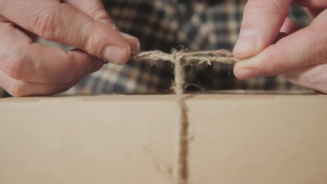 close-up of tying the twine on the bow. packing of finished products butterfly tie made of wool. Good looking young man working as a tailor and using a sewing machine in a textile studio.