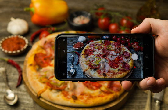 Man taking photo of pizza on smartphone 