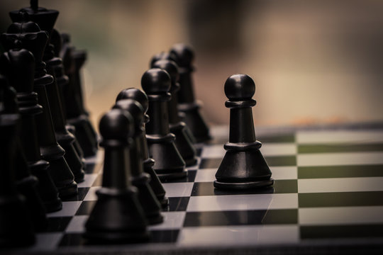 Chess pieces on the black and white board. Black pawn are leader to fight with teamwork to victory.