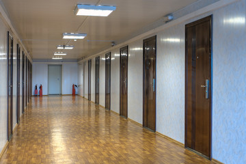 Empty office corridor with many doors of dark red  wood.