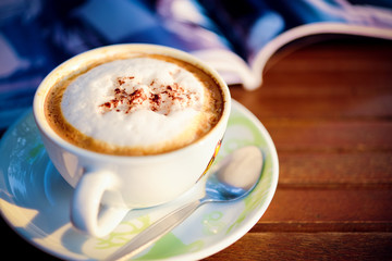 Cup of coffee on table in the morning with book