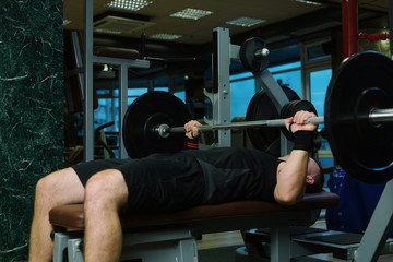 Close-up of a man holding his hands with a barbell for pulling, squatting, fitness in the gym. Concept sports, toned picture, copyspace for text