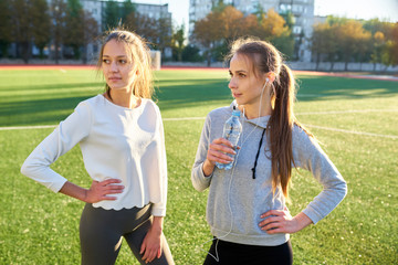 Two sports girls stand and rest after exercise.