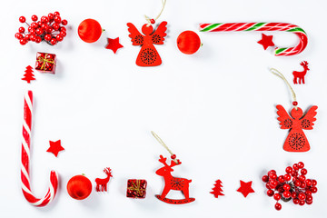Christmas frame made of red toys and New Year decorations on white background. Flat lay, top view, free space. Merry christmas card