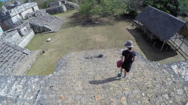 Gimbal shot of a woman walking in mayan ruins in ek balam