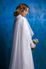 Pretty bride in white wedding dress with bouquet in hands
