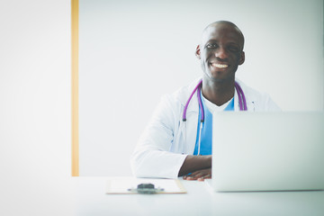 Portrait of young male doctor wearing headset while using computer at desk in clinic. Doctor.