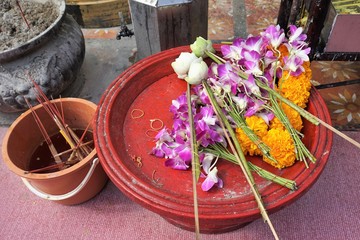 Buddhist requisites with flowers at temple in Thailand