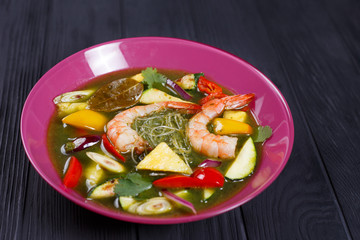 Appetizing green curry soup with prawns and rice noodles, close up. Pan-Asian, thai food, oriental cuisine, tasty appetizing seafood