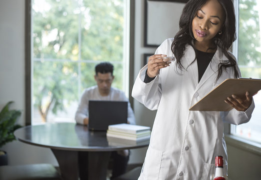 Female Scientist In A Lab Coat Researching With Her Male Coed Med School Student In A Campus Laboratory.  The Woman Is Learning Science And Technology In Medical Industry.