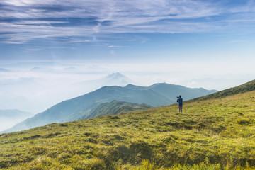 Fototapeta na wymiar A hiker admiring and watching a foggy mountain view, Brescia province, Lombardy district, Italy