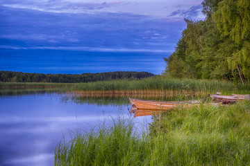 Travel Ideas and Concepts. Peaceful Picturesque Landscape of The Strusto Lake with Wooden Boats at Foreground. Lake is a Part of National Braslav Lakes Nature Reserve.