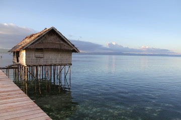 Beautiful Sunset with Ocean Over-Water Bungalows and Trees in Raja Ampat Indonesia