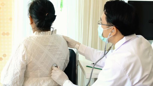 Young doctor used stethoscope listening on back of female patient
