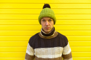Young handsome man against yellow-painted wooden wall