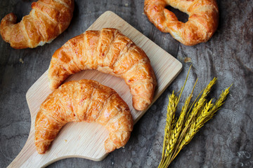 freshly baked croissants on wooden cutting board, top view