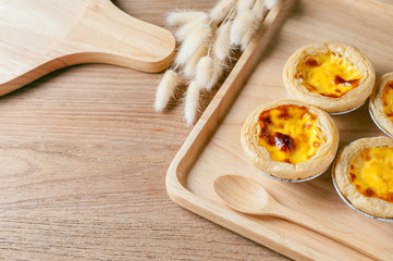 Delicious Egg tart, traditional Portuguese dessert, on wooden plate for coffee break on rustic wooden table.