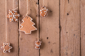 Christmas gingerbread hanging over wooden background.