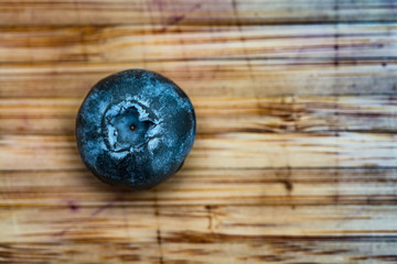 single blueberry on wood cutting board