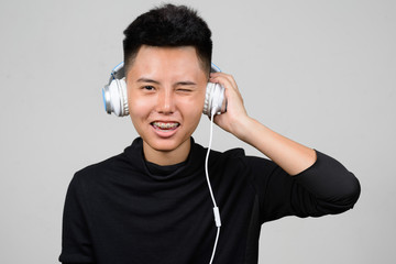 Portrait of Asian young tomboy using headphones and listening music