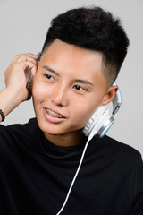 Portrait of Asian young tomboy using headphones and listening music