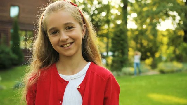 Close up of a pretty young schoolgirl turning her head to the camera and looking into the camera. Sunny summer day. outdoors