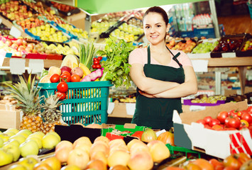 salesgirl in store with basket filled with fresh fruits and vegetables