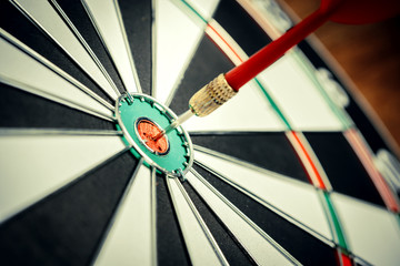 Dart arrow hitting in the target center of dartboard