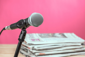 Microphone with newspaper on wooden table - announcement concept