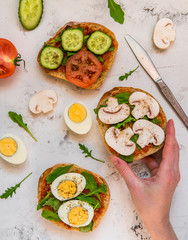 Sandwiches for breakfast. Ciabatta with arugula, egg, mushrooms, cucumbers and tomatoes