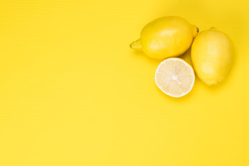 lemons and their half lie on a yellow background