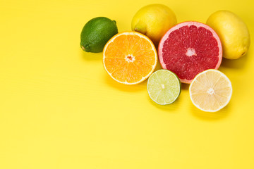 red grapefruit, orange orange and yellow and green slices of lime, on a yellow background