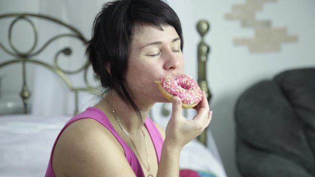 woman eating a donut on a bed, breakfast with junk food