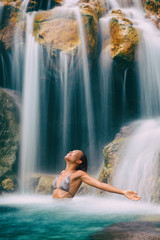 Waterfall woman meditation carefree with open arms. Zen woman meditating in relaxing water bikini woman feeling carefree in fresh tropical lush forest relaxation destination.
