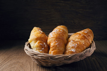 Fresh baked croissant sprinkled with powdered sugar on table