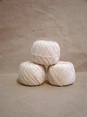 Beads of beige yarn on gray paper close up