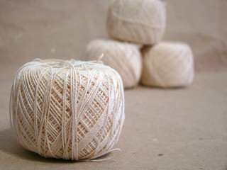 Beads of beige yarn on gray paper close up