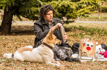 young caucasian man with afro hairstyle on the picnic with his dog