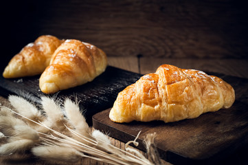 Fresh baked croissant sprinkled with powdered sugar on table
