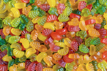 background of many bright and colored jelly sweets with free space for text, top view