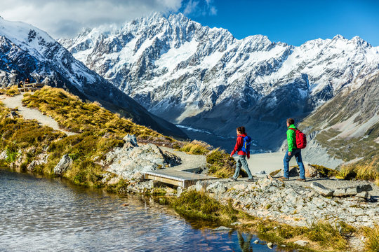 Hiking travel nature hikers in New Zealand mountains. Mount Cook landscape. Couple people walking on Sealy Tarns hike trail route towards Mueller Hut, famous tourist attraction.
