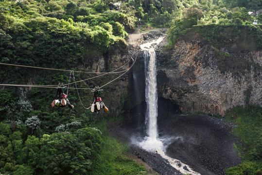 Fototapeta Tourists gliding on the zip line trip against Bridal veil (Manto de la novia), waterfall in Cascades route, Banos, Ecuador