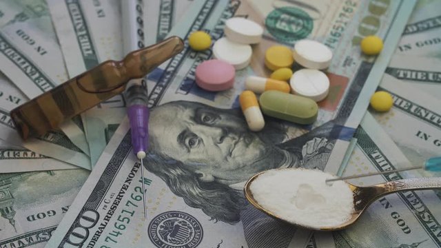 Drugs and pills for addiction lie on the thousands of paper dollars 