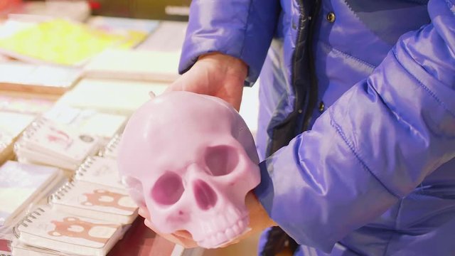 Woman's hands hold souvenier candle holder in form of skull