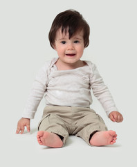 Funny baby sitting on the floor, isolated over white