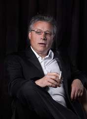 senior businessman with a cigarette,sitting in a chair