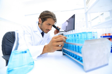 Chemist looking at test-tubes with blue liquids