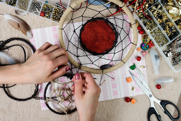 Woman is engaged in needlework. Does the dream catcher. View from above
